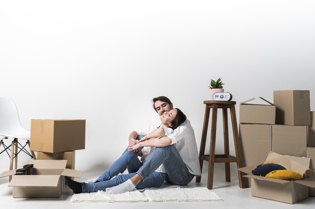 Женщина в носках, держит коробку с растением на картонной подставке.