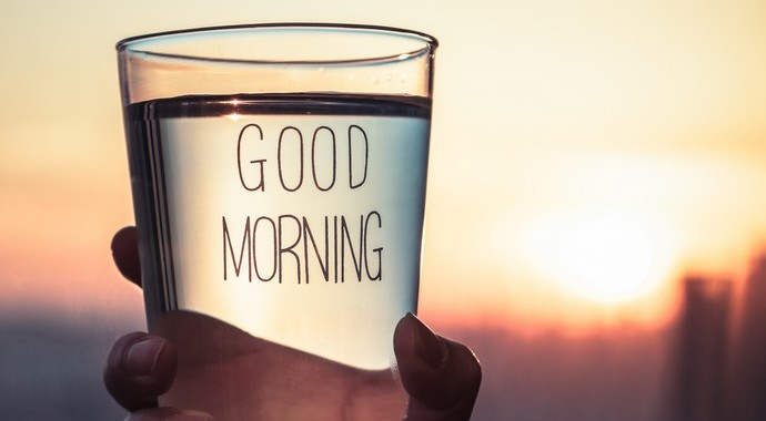 Стакан с алкоголем в руках человека, наполненный жидкостью, напоминающей стекло.