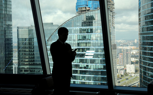 Городской пейзаж с высокими зданиями, офисными башнями и взрослым мужчиной.