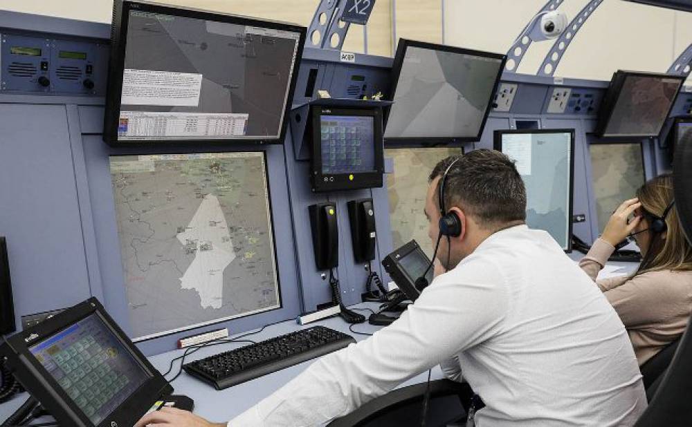 Женщина с гарнитурой играет на компьютере, видно клавиатуру и монитор.