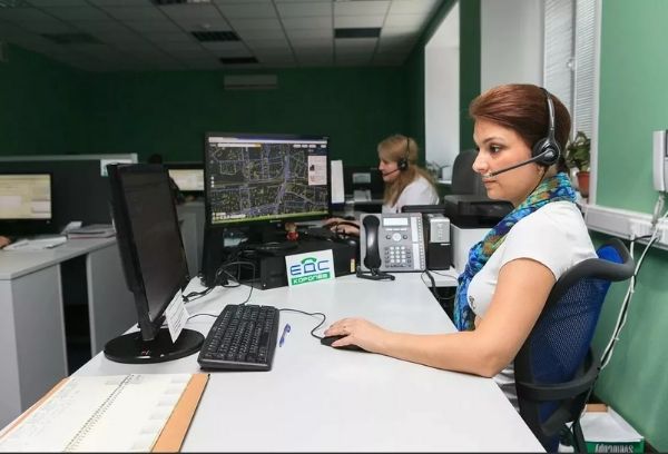 Клавиатура компьютера, взрослая женщина сидит перед монитором, в наушниках.