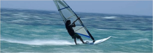 Пейзаж с морем, человеком на серфе и парусником на фоне.