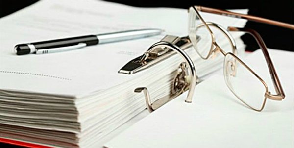 Аксессуары: очки, текст, ручка, папка с документами. Концепция офиса и рабочего пространства.