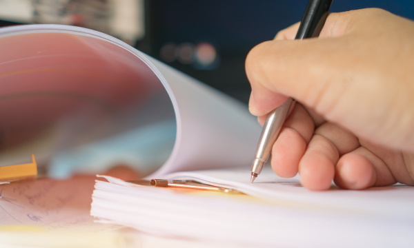 Человек пишет ручкой, держа ребенка на руках.