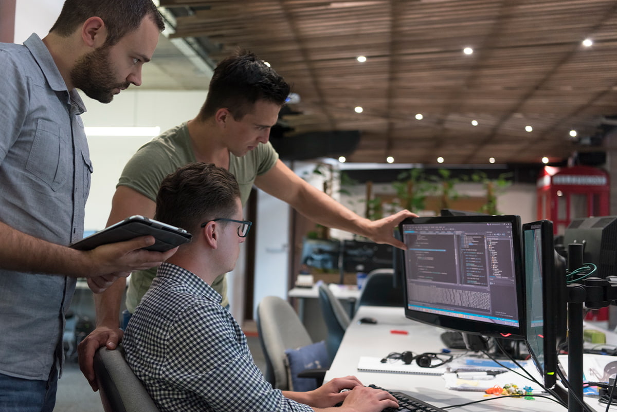 Мужчина в очках за столом с монитором, лицо в кадре, в джинсах.