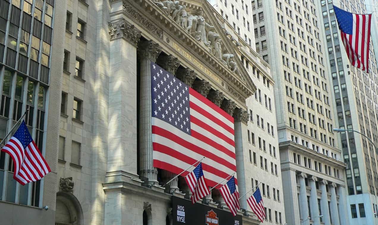 Американский флаг на фоне городской застройки с офисными зданиями и архитектурой.