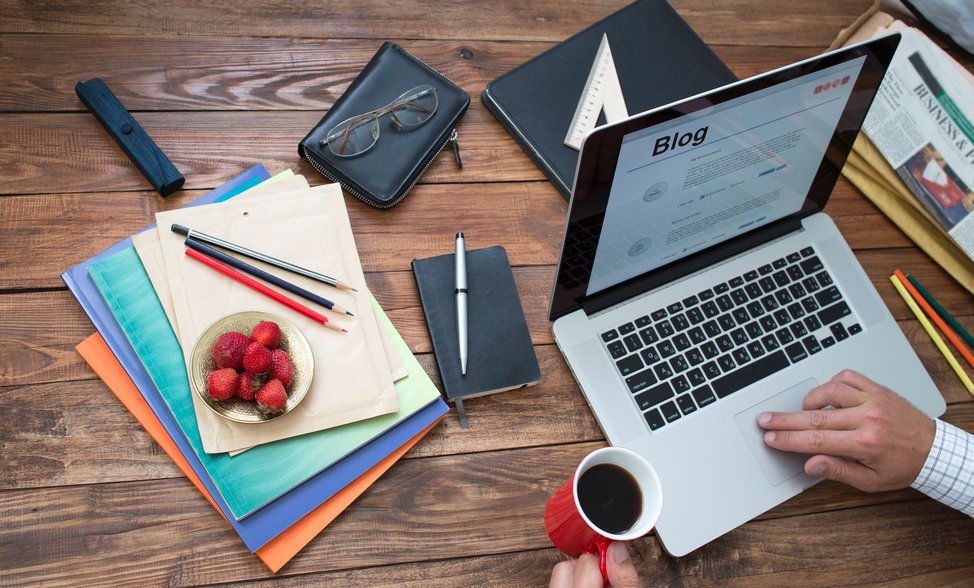 Фото ноутбука с аксессуарами, кошельком, текстом, ручкой, мебелью и кофейной чашкой.