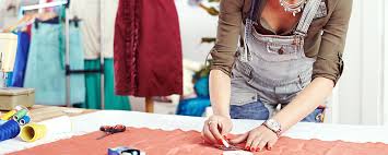 Младенец в жилетке, с рукой на теле, одет в одежду, находится в помещении.