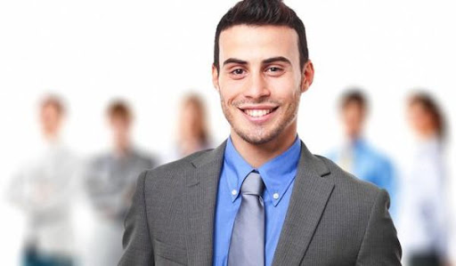 Человек в формальной одежде с улыбкой, галстуком и морщинками на лице.