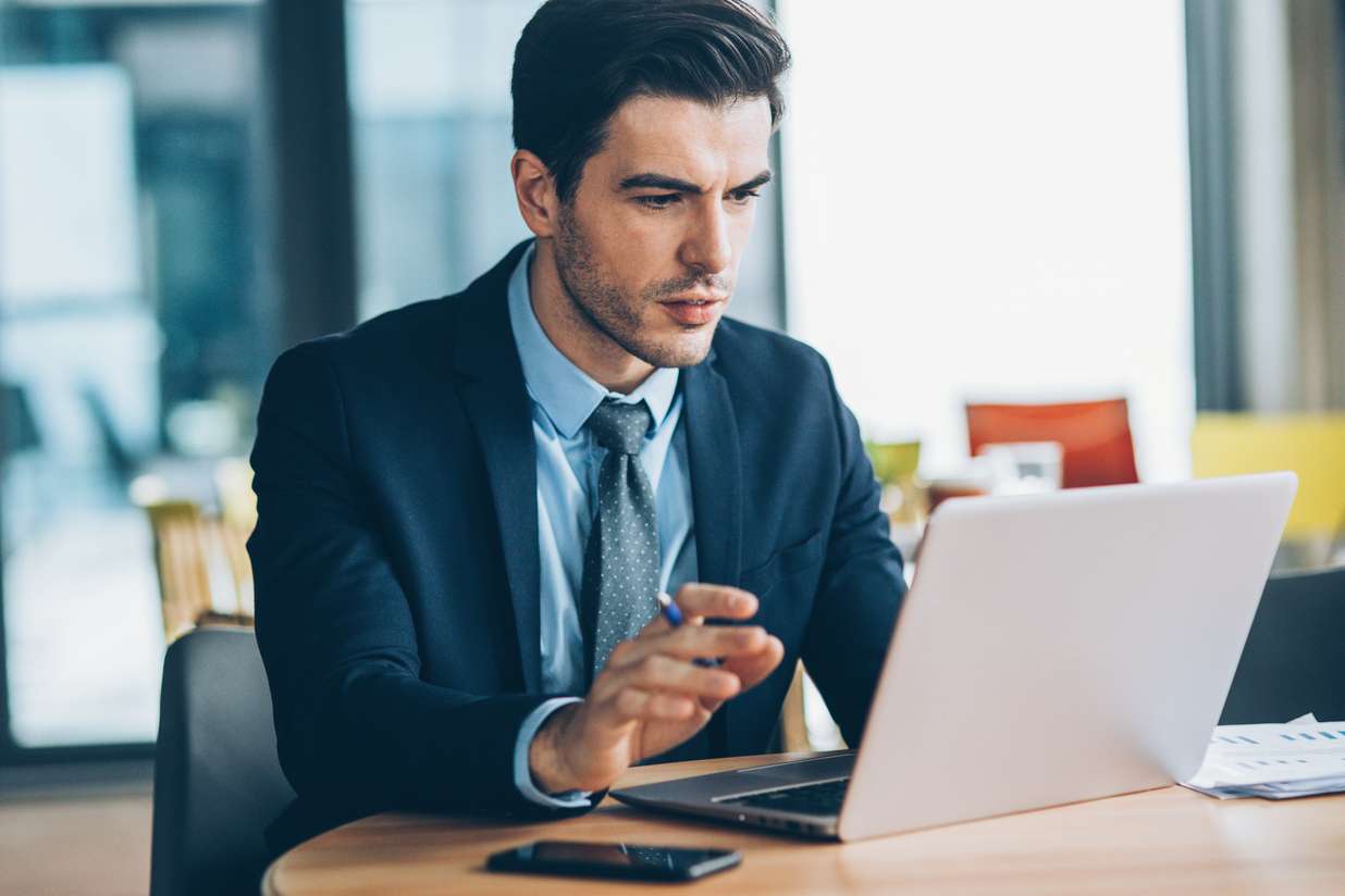 Исполнитель в костюме с мобильным телефоном и ноутбуком, мужчина в галстуке.