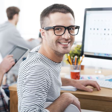 Мужчина в очках с улыбкой за компьютером, фотопортрет.