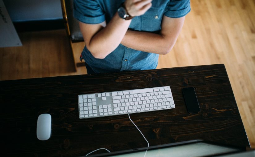 Деревянный стол с компьютером, ноутбуком, клавиатурой и мобильным телефоном на деревянном столе.