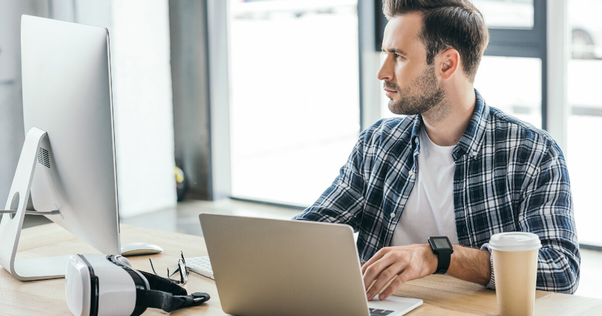 Электроника: исполнитель с ноутбуком, чашкой, сидящий, смотрящий в ноутбук.