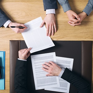 Человек-мужчина пишет текст на документе с помощью ручки.