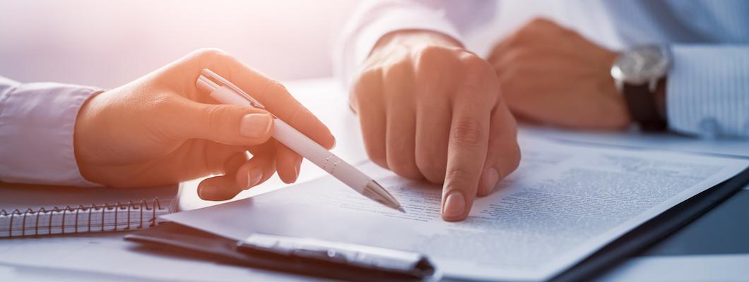 Человек пишет текст ручкой на бумаге.