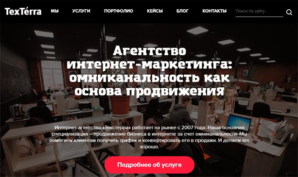 Люди работают за компьютерами в классе с учебными столами и стульями.