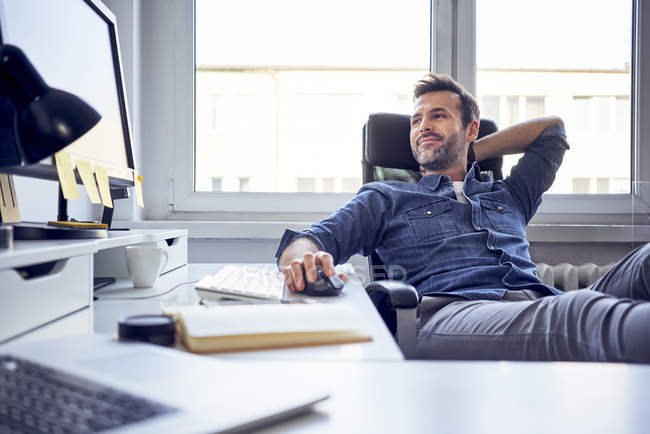 Человек сидит за компьютером, работает с железом, клавиатурой и другой электроникой.