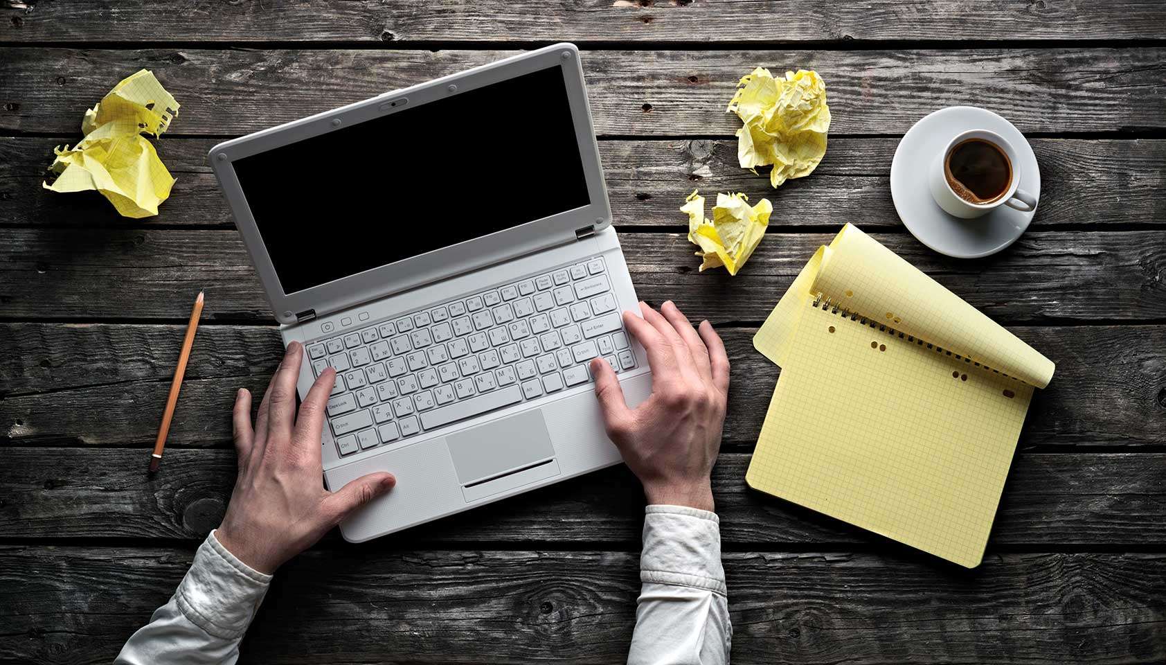 Ноутбук на столе с кофе, розой и кошельком, компьютерная клавиатура в фоне.