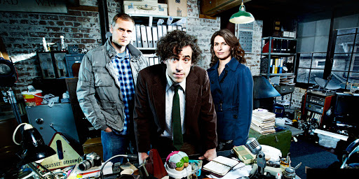 Мужчина в пальто за столом с человеком в галстуке.