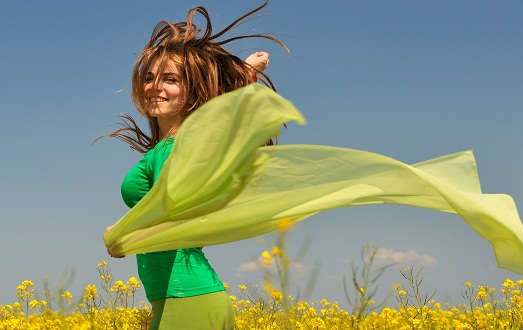 Человек в темно-синем пальто на траве, в руках держит белую футболку.