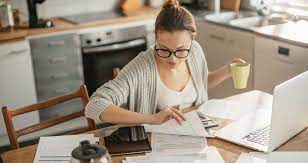 Женщина на стуле пользуется ноутбуком в кресле, рядом электроника и мебель.