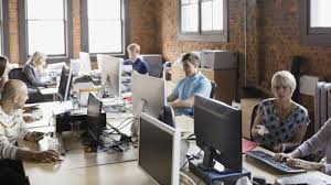 "Female adult holding baby in front of computer monitor indoors."
