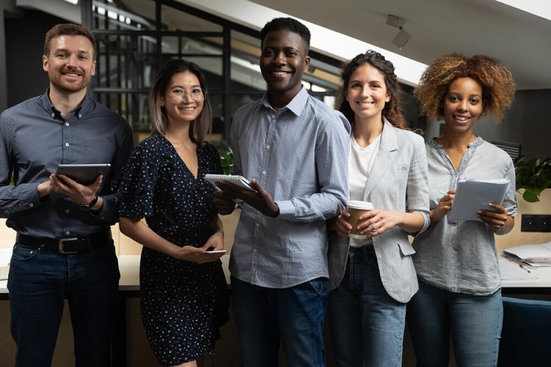 "Groupshot of adults with a woman and man using a tablet computer outdoors."