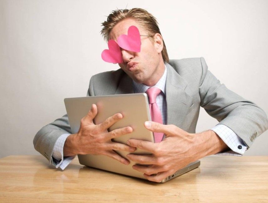 Взрослый мужчина в формальной одежде с галстуком, смотрящий на планшетный компьютер.