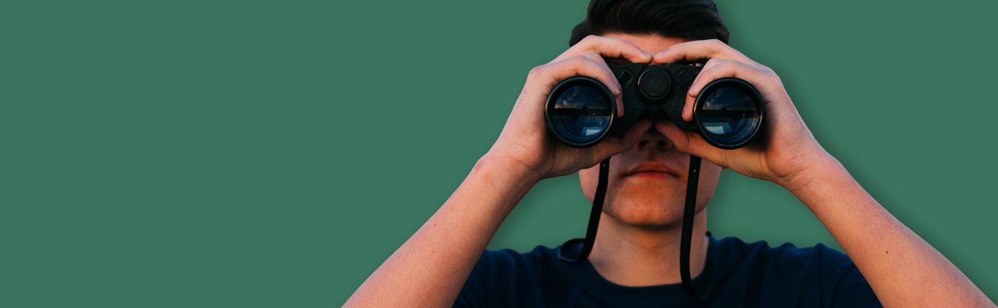 Фотография взрослого мужчины с биноклем, лицо и голова видны на фоне.