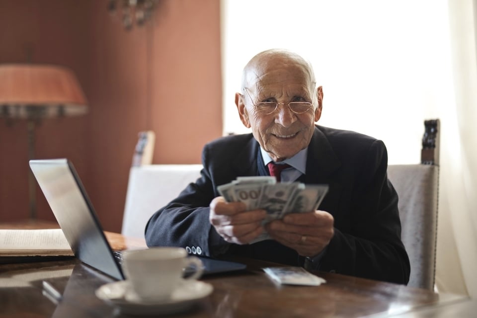 Man wearing formal wear with glasses and tie holding a cup on a plate.