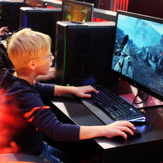 Мальчик-ребенок за компьютером: монитор, клавиатура, видеоигры.