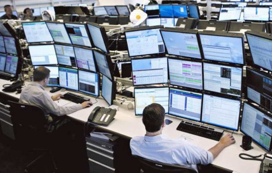 Взрослый мужчина за компьютерным столом, смотрит на монитор и набирает текст на клавиатуре.