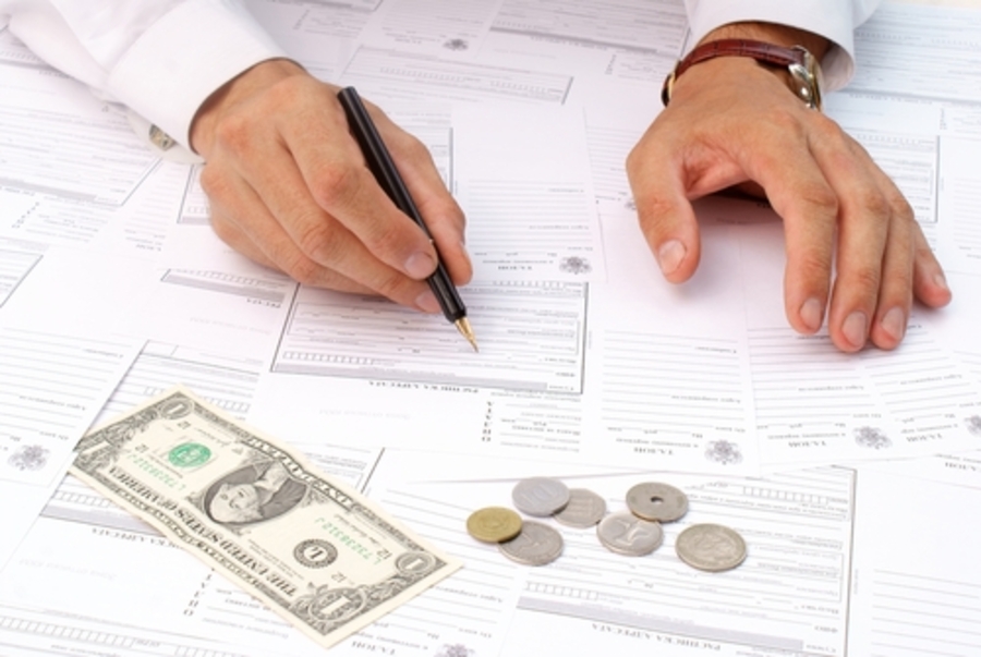 Человек держит ручку, пишет на документе, видно голову и лицо.