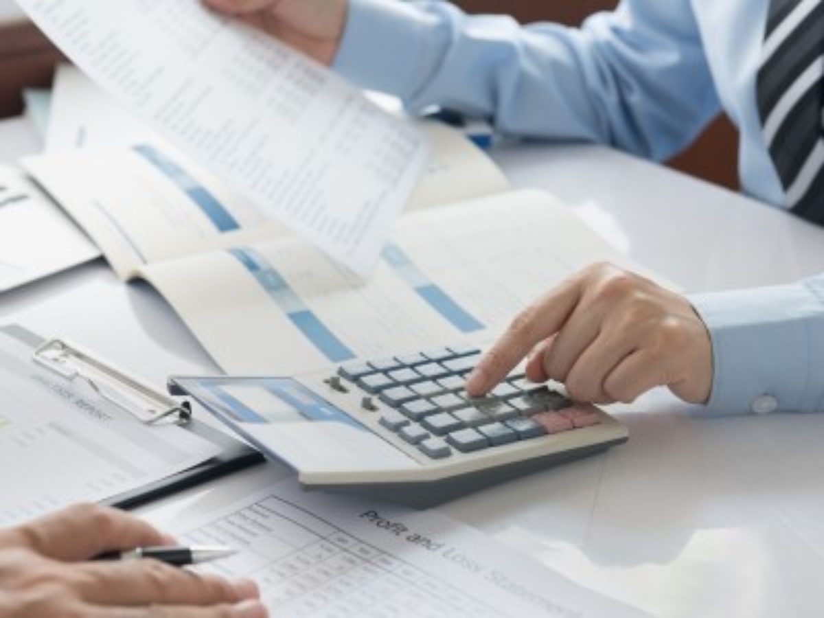 Человек пишет текст ручкой на документе.