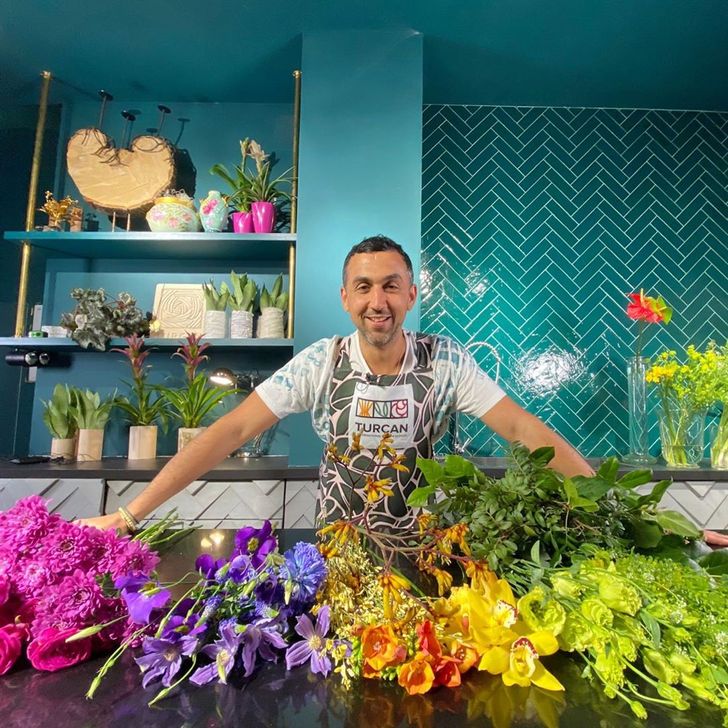 Человек в одежде повара с одиночным выступлением, держащий букет цветов.