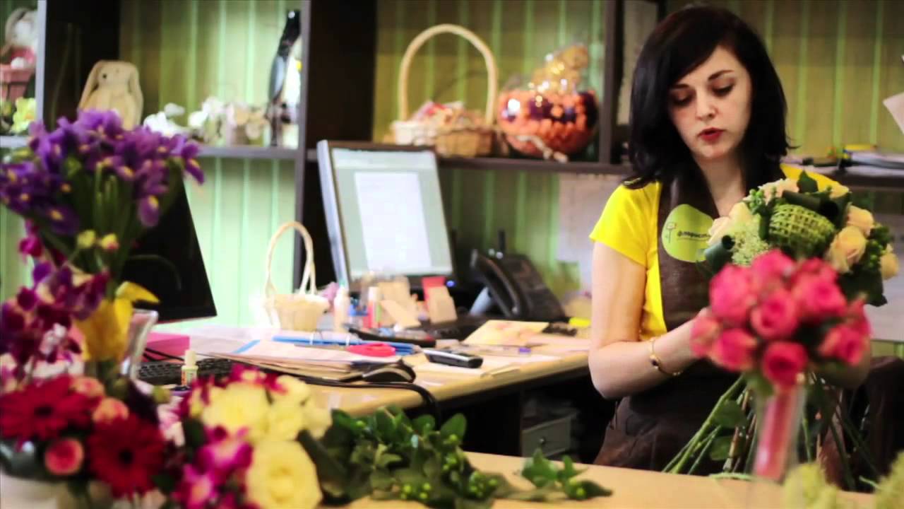 Композиция цветов на столе с женщиной в магазине.