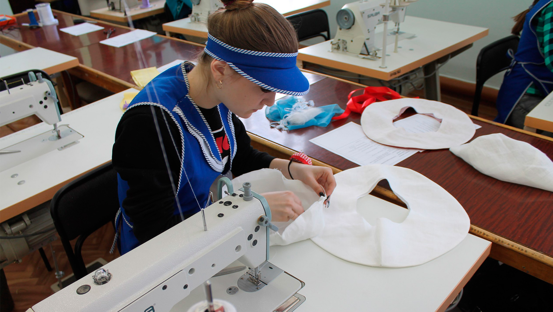 Человек шьет, лицо сосредоточено на работе, изображение головы.