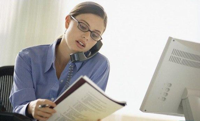 Женщина-руководитель, читающая книгу. Серьезное лицо, выразительный взгляд.