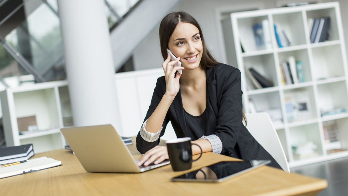 Исполнитель сидит за ноутбуком с чашкой кофе на столе.