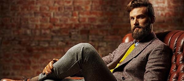 Голова и лицо человека в официальной одежде с галстуком, бородой, в пиджаке, сидящего.