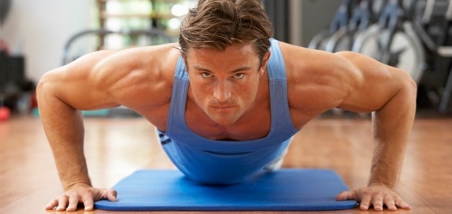 Мужчина в возрасте выполняет упражнение "отжимания" во время занятий фитнесом.