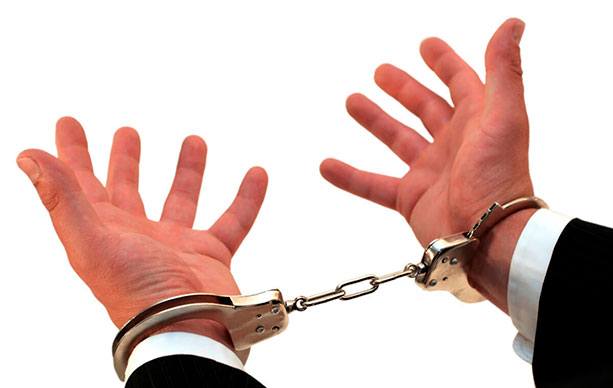 Человек в наручниках, показывает палец рукой.