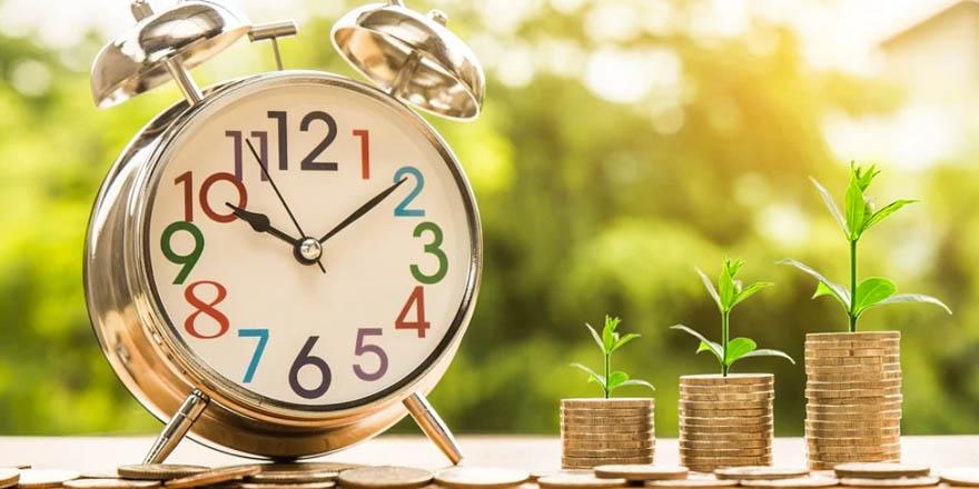 Будильник на столе с растением - время наступает.