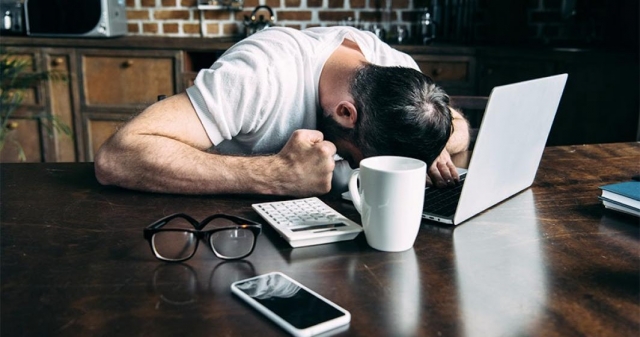 Фотография взрослого мужчины с мобильным телефоном в руке, чашкой и микроволновкой.