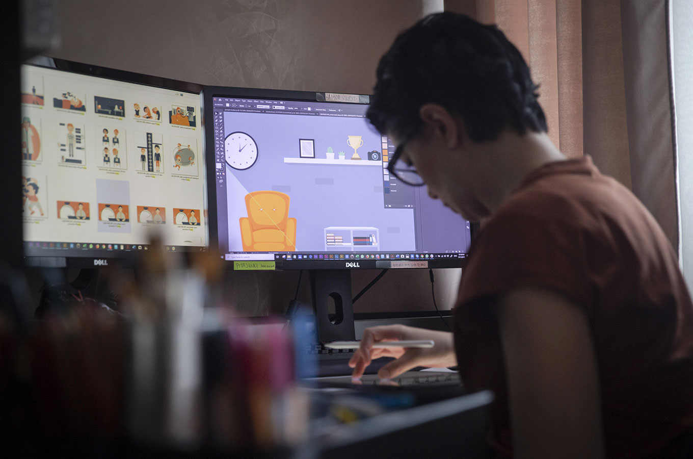 Человек за столом с компьютером, монитором и CAD-диаграммой на экране.