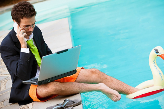 Мужчина сидит за ноутбуком, сосредоточенно смотрит на экран, в галстуке.