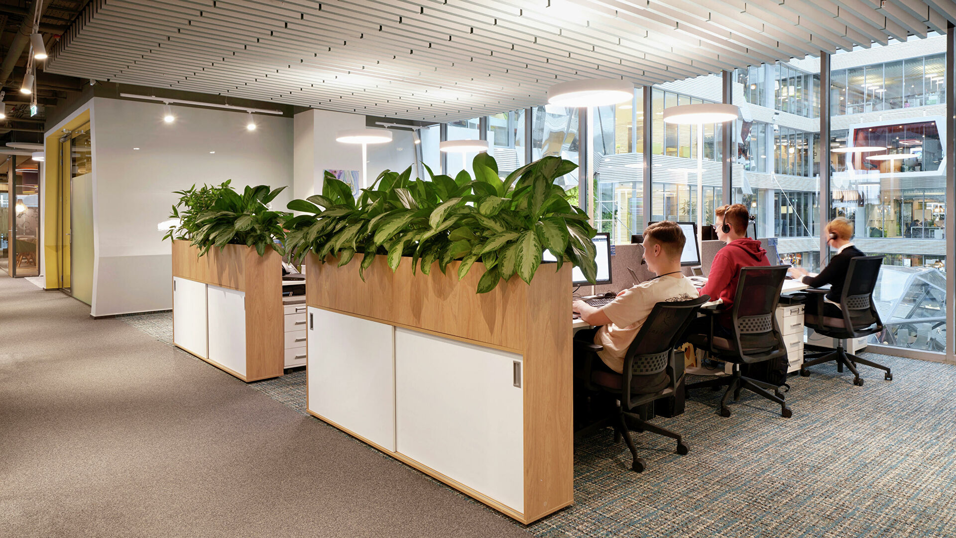 Интерьер кафе с мебелью, растениями и человеком в помещении.