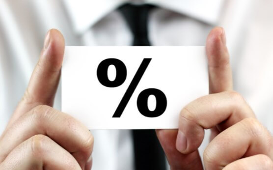 Человек в деловом костюме держит бумагу с цифрой и символом на фоне руки.