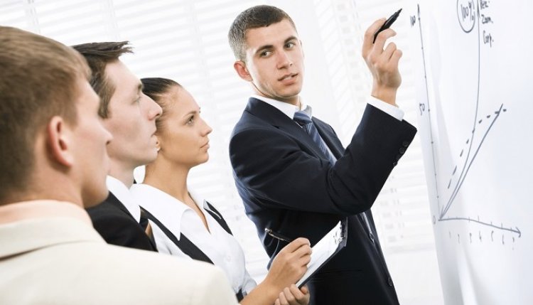 Взрослая женщина и мужчина в деловой одежде с аксессуарами у белой доски.