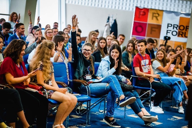 Женщина с сумкой в руке, держащая очки, стоит близком, обутая в туфли.